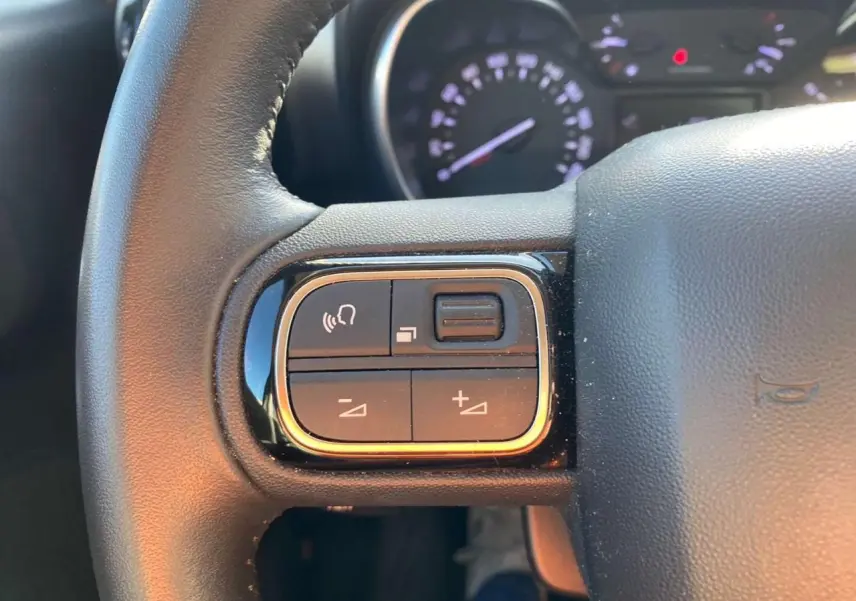 Gros plan sur la partie gauche du volant noir du Citroën C3 Aircross 2024 avec commandes audio intégrées.