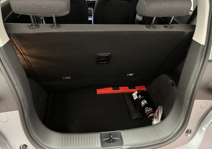 Coffre ouvert d'une Renault ZOE blanche 2024, vue arrière montrant un espace de rangement avec accessoires de sécurité.