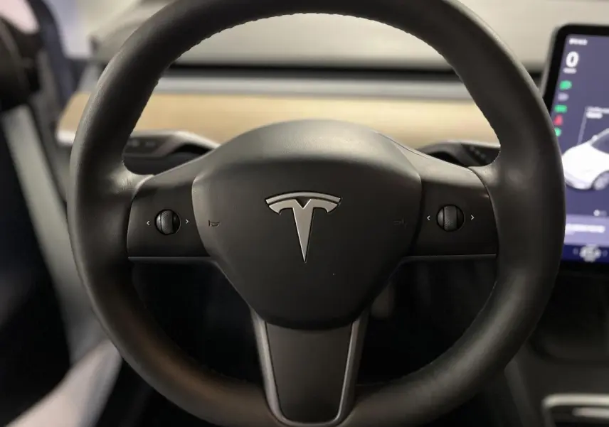 Volant noir Tesla Model Y 2022 en gros plan avec logo central et écran tactile partiel visible à droite