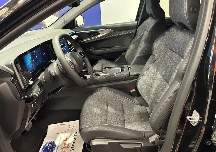 Intérieur côté conducteur du Renault Austral Ph.2 noir étoilé, sièges tissu et cuir gris avec tableau de bord digital moderne.