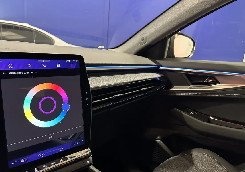 Intérieur côté passager du Renault Austral Ph.2 noir étoilé, avec écran tactile et éclairage d'ambiance bleu sur la planche de bord.