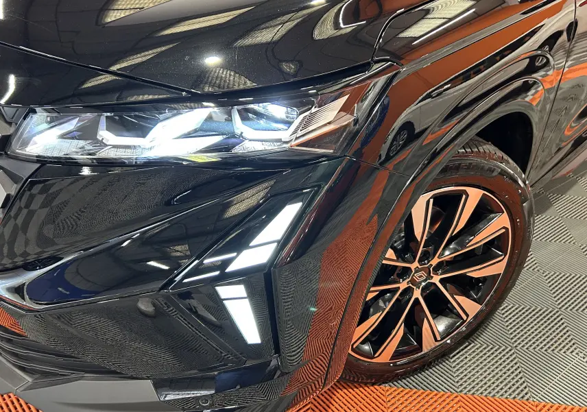 Gros plan sur l'avant droit noir étoilé du Renault Austral Ph.2 E-TECH avec phares LED et jante alliage bicolore.