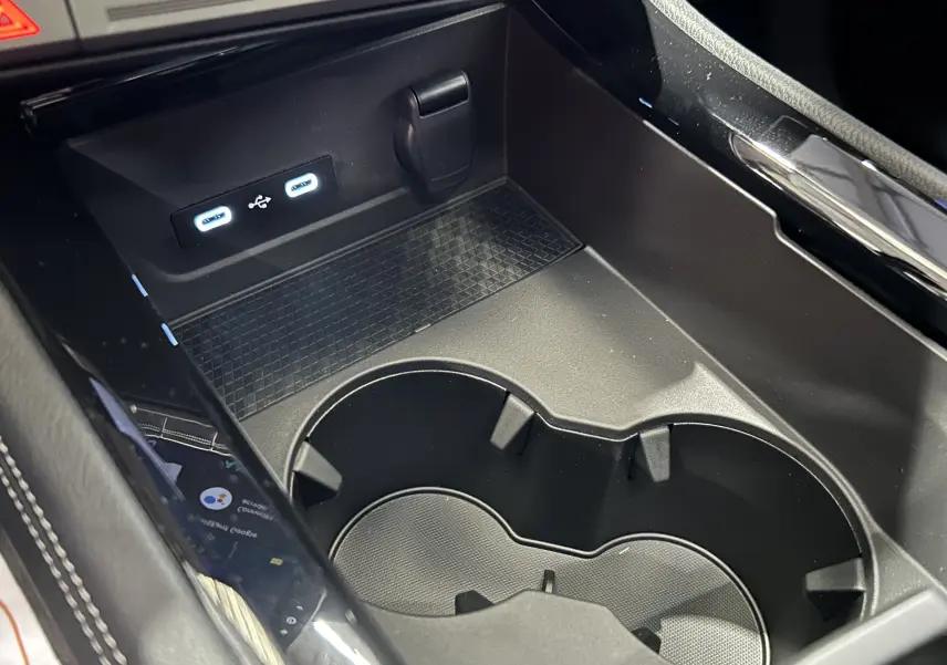 Gros plan sur la console centrale noire étoilé du Renault Austral Ph.2 avec prises USB et porte-gobelets intégrés.