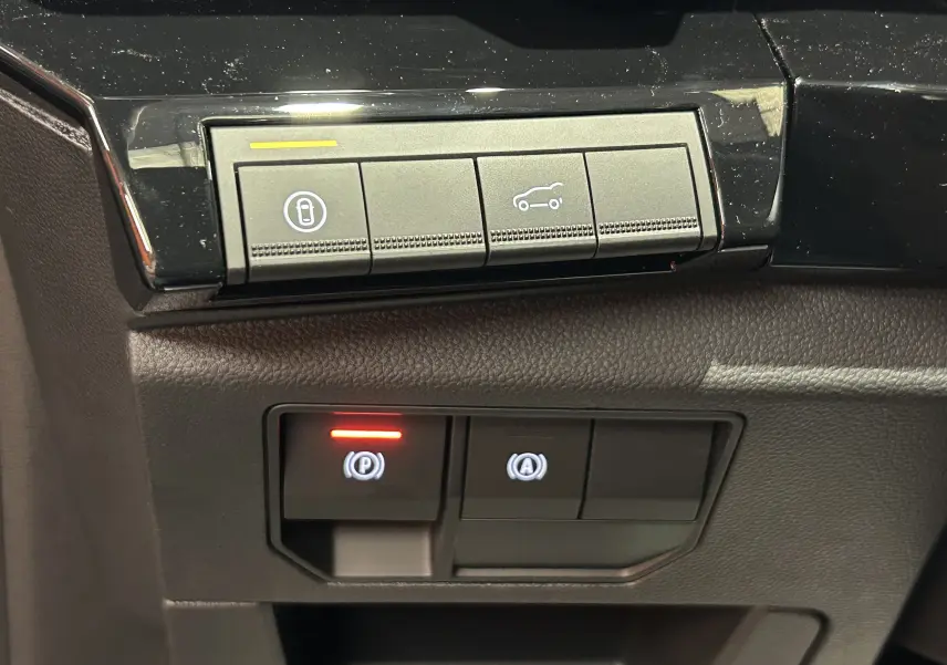 Gros plan sur les boutons de commande du hayon électrique et du frein à main dans l'habitacle du Renault Austral noir étoilé.