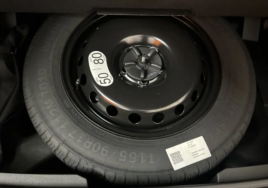 Gros plan sur la roue de secours noire avec étiquette de limitation de vitesse dans le coffre du Renault Austral 2025 noir étoilé.