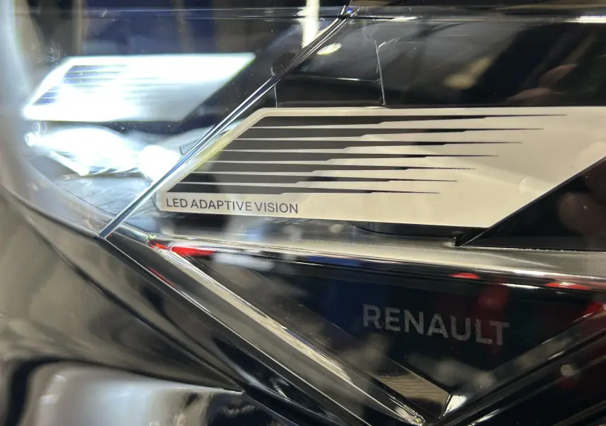 Gros plan sur le phare LED Adaptive Vision noir étoilé du Renault Austral Ph.2 hybride avec logo Renault visible.