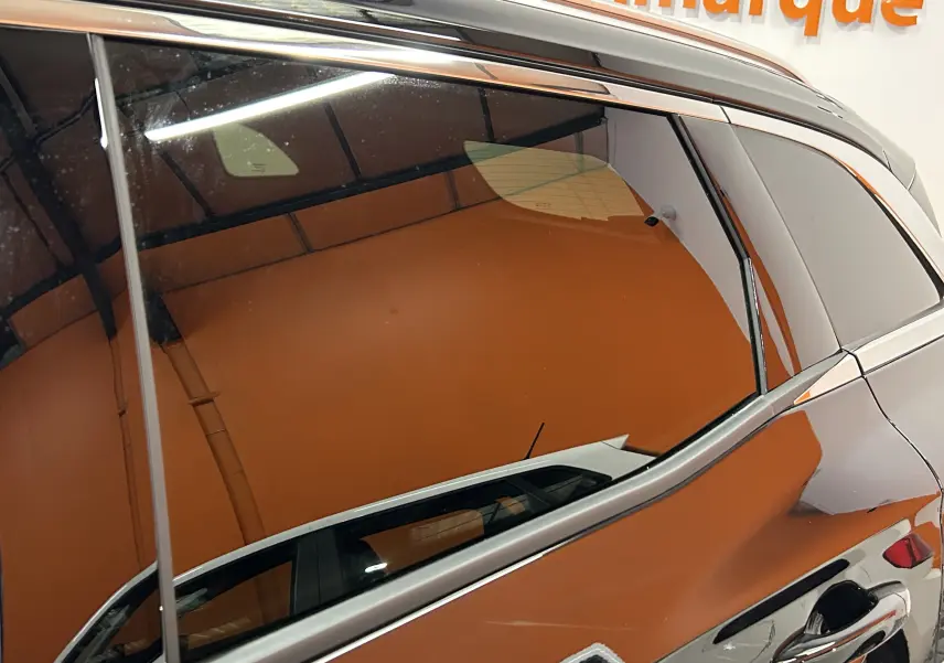 Reflet sur la vitre arrière côté droit d'un Renault Austral noir étoilé, avec poignée de porte visible en gros plan.