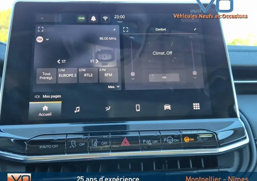 Écran tactile central du Jeep Compass gris 2024 montrant radio FM et commandes climatisation dans l'habitacle.