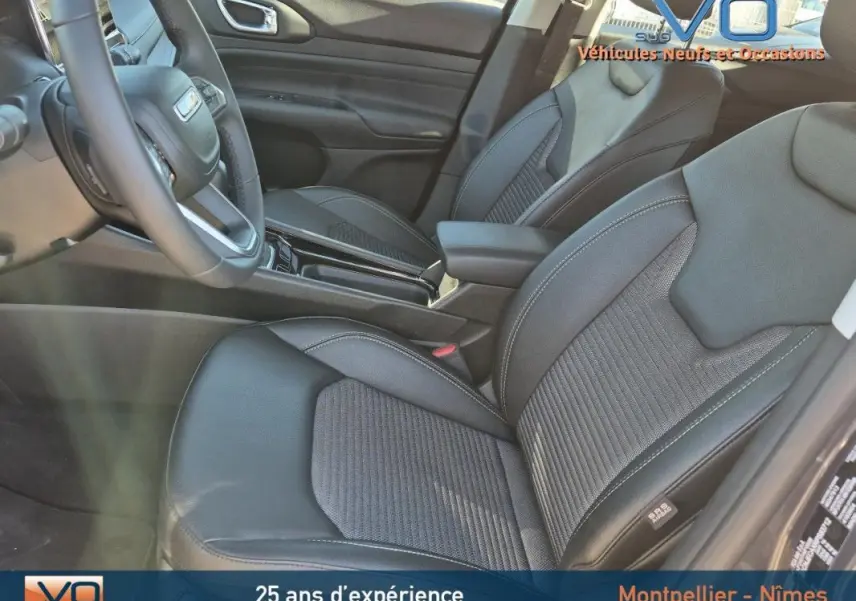 Intérieur avant droit du Jeep Compass 2024 gris, montrant sièges en cuir noir et accoudoir central.