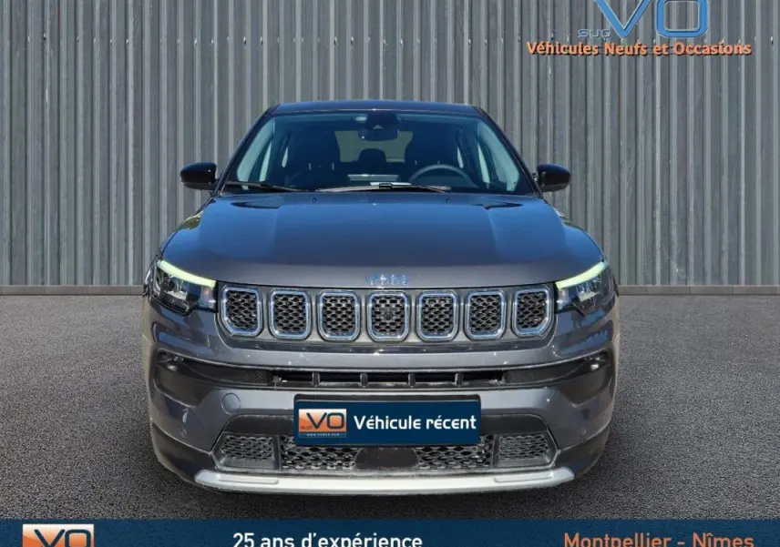 Vue frontale d'un Jeep Compass gris 2024 avec calandre à sept fentes et phares LED allumés.