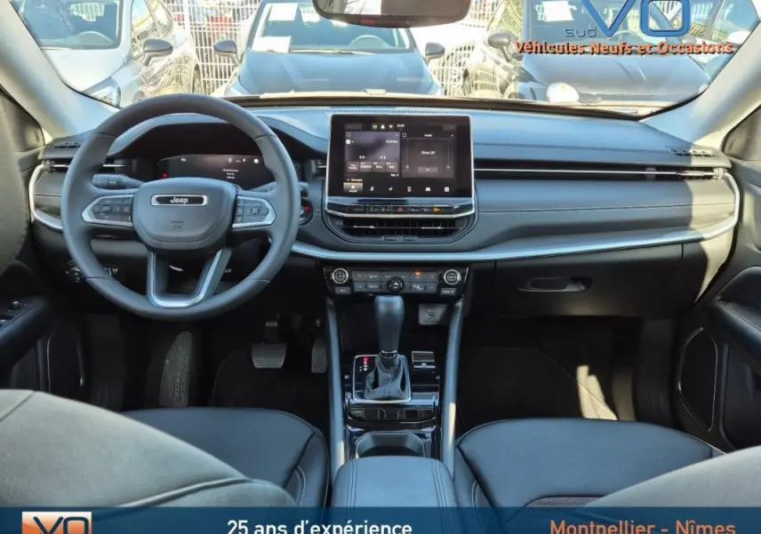 Vue intérieure frontale du tableau de bord et volant du Jeep Compass gris 2024 avec écran tactile et boîte auto.