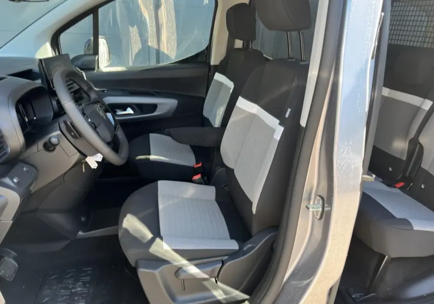 Vue intérieure côté gauche du Citroën Berlingo gris Artense, montrant les sièges tissu bicolores et le volant multifonctions cuir.