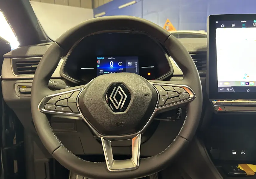 Vue rapprochée du volant multifonction noir du Renault Captur II Ph.2 TECHNO avec tableau de bord digital et écran tactile.