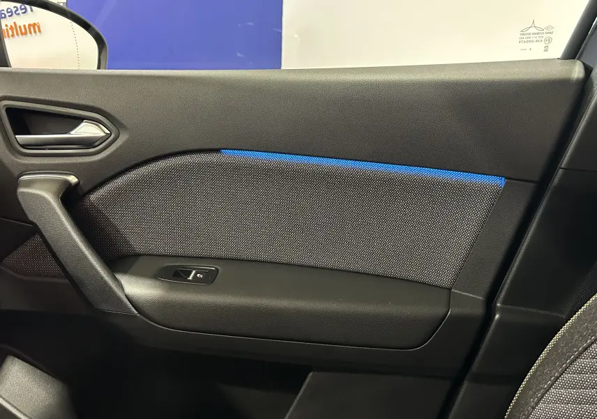 Vue intérieure côté gauche de la porte d'une Renault Captur II Ph.2 TECHNO noire avec éclairage d'ambiance bleu.