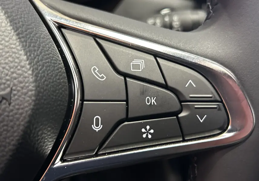 Gros plan sur les commandes multifonctions noires et chromées du volant du Renault Captur II Ph.2 TECHNO 2025.