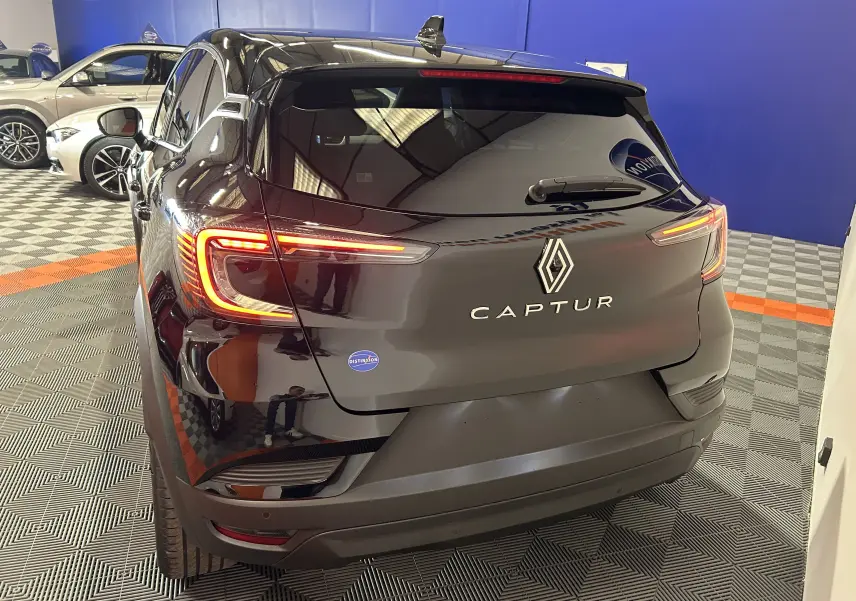 Vue 3/4 arrière d'un Renault Captur noir étoilé 2025 avec feux arrière allumés dans un showroom.