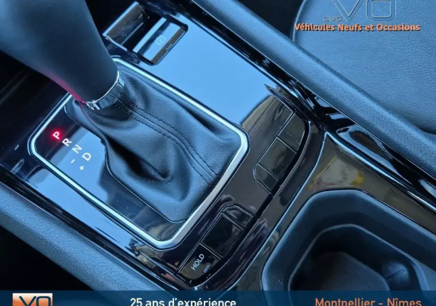 Gros plan sur la console centrale noire du Jeep Compass 2024 avec levier de vitesse automatique et accoudoir gris.