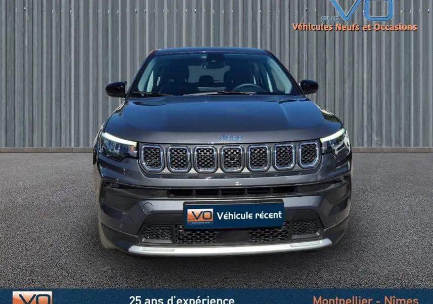 Vue frontale d'un Jeep Compass gris 2024 avec calandre à sept fentes et phares LED allumés.