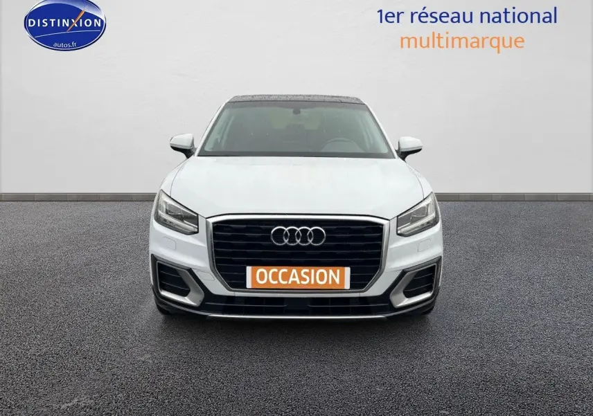 Vue avant d'un Audi Q2 blanc Ibis avec calandre noire et plaque orange "OCCASION" sur un sol gris.