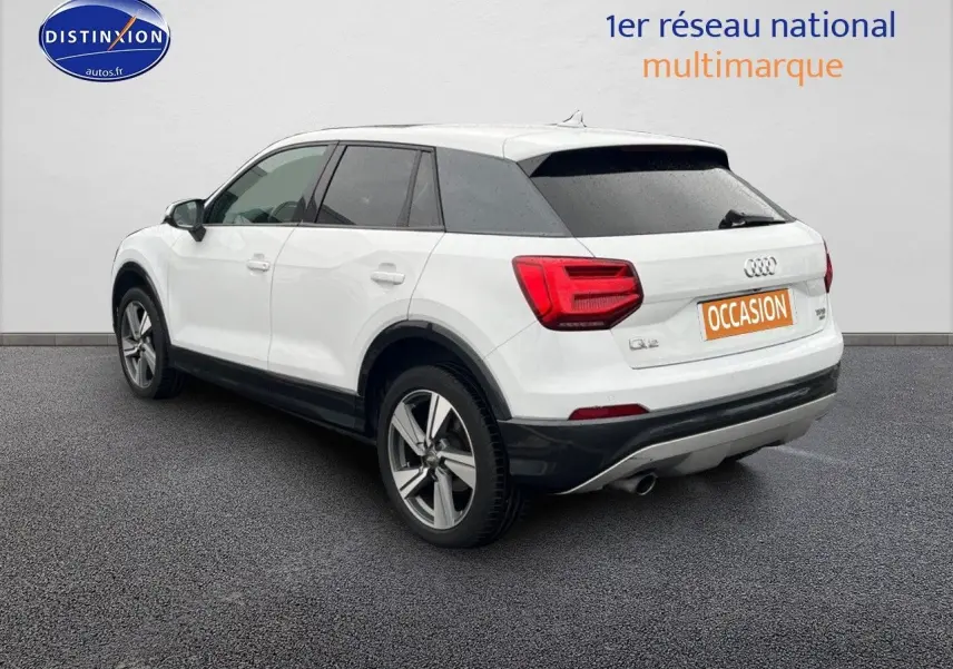 Vue 3/4 arrière droite d'un Audi Q2 blanc Ibis avec jantes alliage 18 pouces et vitres surteintées.