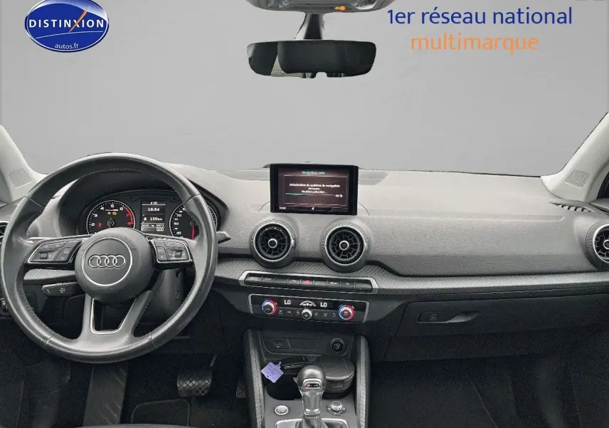 Vue intérieure avant de l'Audi Q2 2018 avec tableau de bord noir, volant cuir multifonction et écran central.