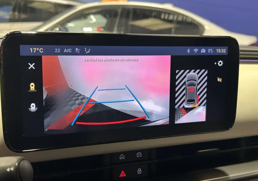 Écran multimédia montrant la caméra de recul avec vue arrière du Fiat 600 bleu hybride 2024 et lignes de guidage colorées.