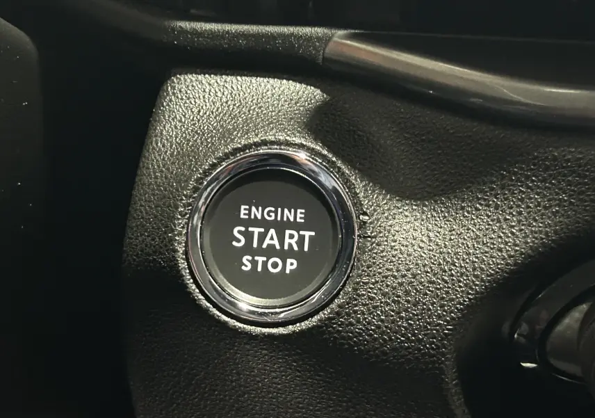 Bouton démarrage moteur "Engine Start Stop" en gros plan sur le tableau de bord noir de la Fiat 600 Hybrid 2024.