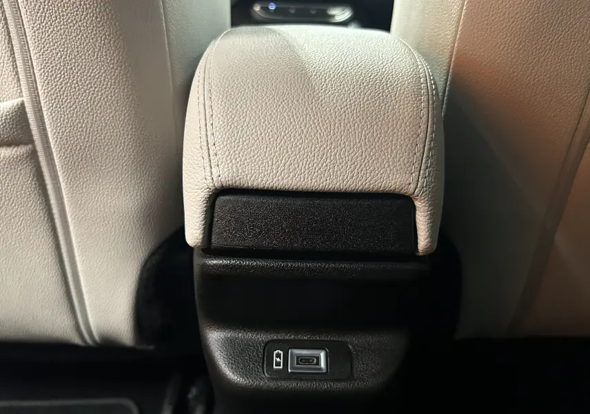 Prise USB en gros plan sur la console arrière entre les sièges en cuir beige d'une Fiat 600 Hybrid 2024.