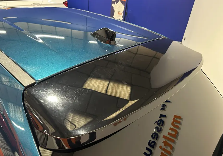 Vue arrière en plongée du toit bleu métallisé et du hayon noir brillant de la FIAT 600 Hybrid 2024 avec antenne shark fin.