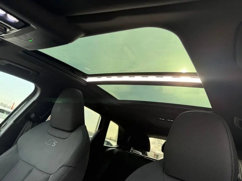 Intérieur de l’Audi Q3 2.0 TDI S line 2026, vue avant sur sièges noirs et toit panoramique ouvrant.