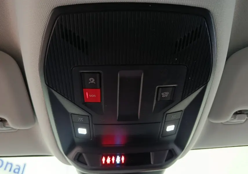 Vue en contre-plongée du panneau de commandes au plafond intérieur du Peugeot 308 gris foncé, avec bouton SOS rouge et éclairages blancs.