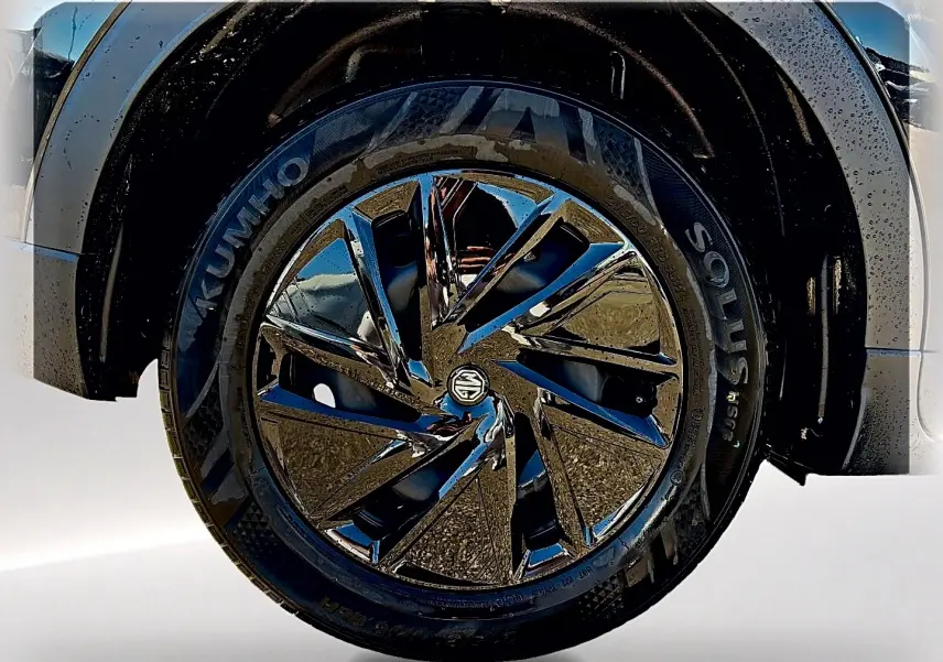 Gros plan sur la roue avant droite noire du MG Motor ZS 1.5 hybrid 197 standard avec jante brillante multifacettes.