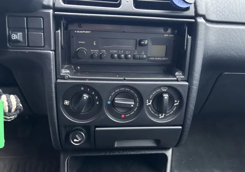 Gros plan sur la console centrale d'une Citroën ZX gris 1992, montrant autoradio Blaupunkt et commandes de climatisation.