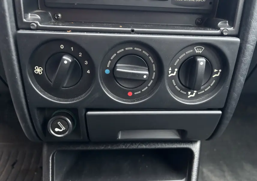 Gros plan sur les commandes de chauffage et ventilation noires du tableau de bord d'une Citroën ZX gris 1992.