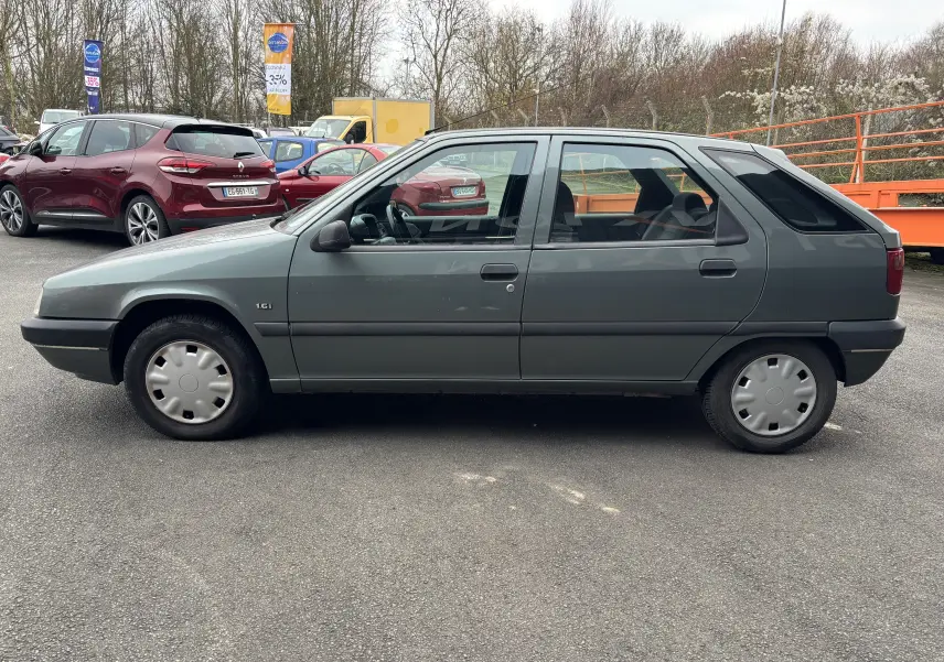 Profil côté gauche d'une Citroën ZX gris 1.6i 89CV de 1992 avec jantes pleines et carrosserie compacte.