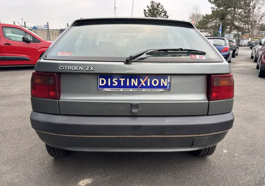 Vue arrière d'une Citroën ZX gris 1992 avec plaque Distinxion et feux arrière rectangulaires rouges.