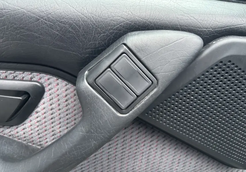 Détail des commandes électriques sur la porte côté gauche d'une Citroën ZX gris 1.6i de 1992 avec tissu à motifs.