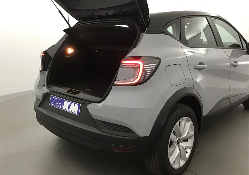 Vue arrière droite du Renault Captur gris Rafale avec coffre ouvert et feux arrière allumés dans un studio.