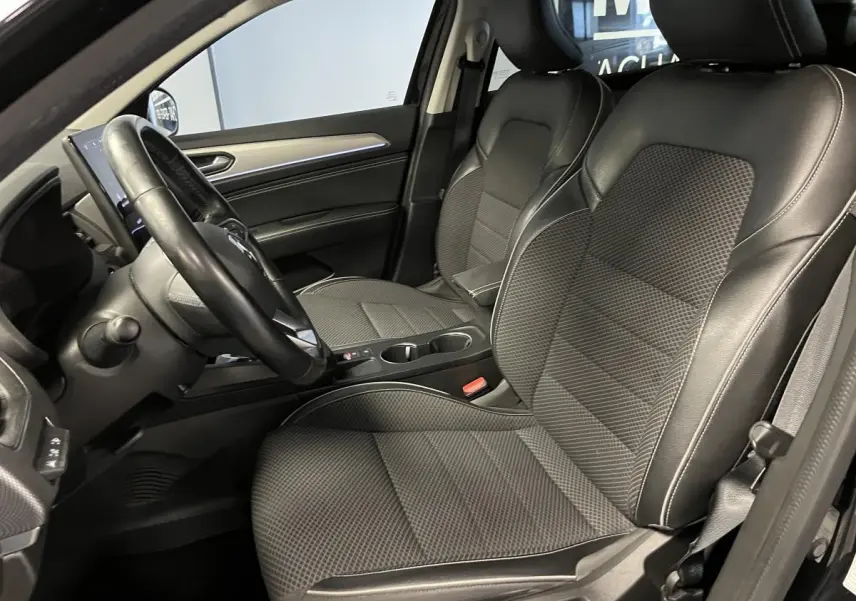 Intérieur avant droit du Renault Arkana noir, sièges tissu/similicuir noirs avec volant cuir et console centrale visible.