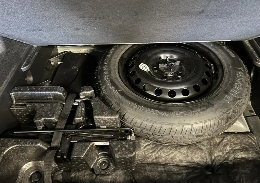 Roue de secours galette noire et outils de bord dans le coffre du Renault Arkana 1.6 E-Tech Hybride noir.