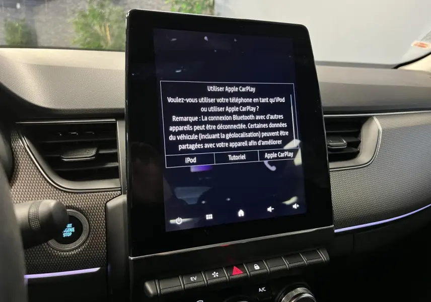 Vue rapprochée de la console centrale noire du Renault Arkana 2021 avec écran tactile affichant Apple CarPlay.