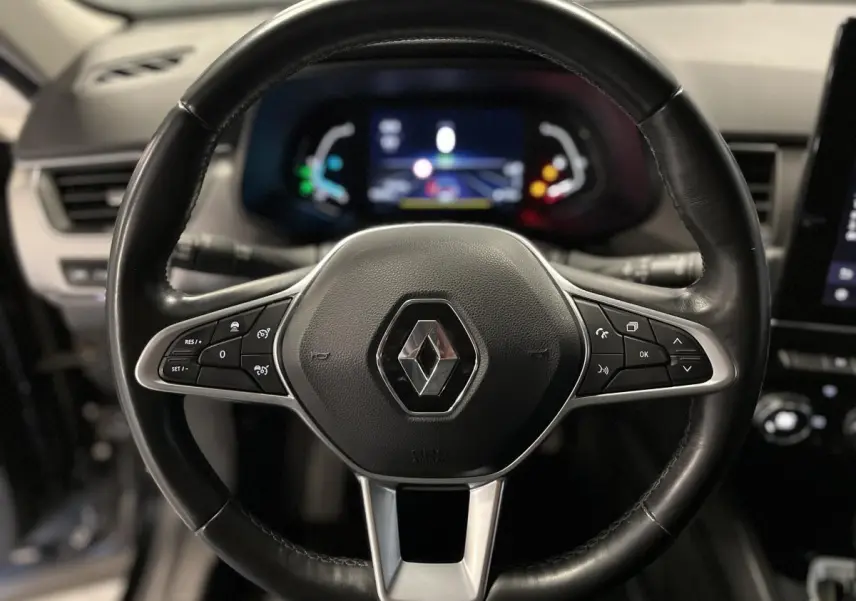 Volant cuir noir de Renault Arkana 2021 vu de face avec commandes intégrées et tableau de bord numérique flou en arrière-plan.