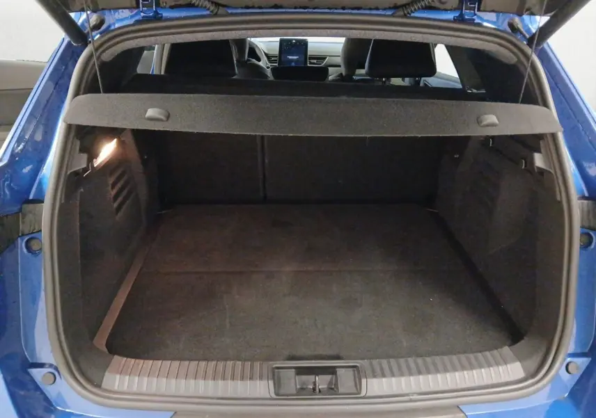 Coffre ouvert vu de l'arrière d'une Renault Symbioz bleu iron, montrant l'espace de chargement et la tablette arrière.