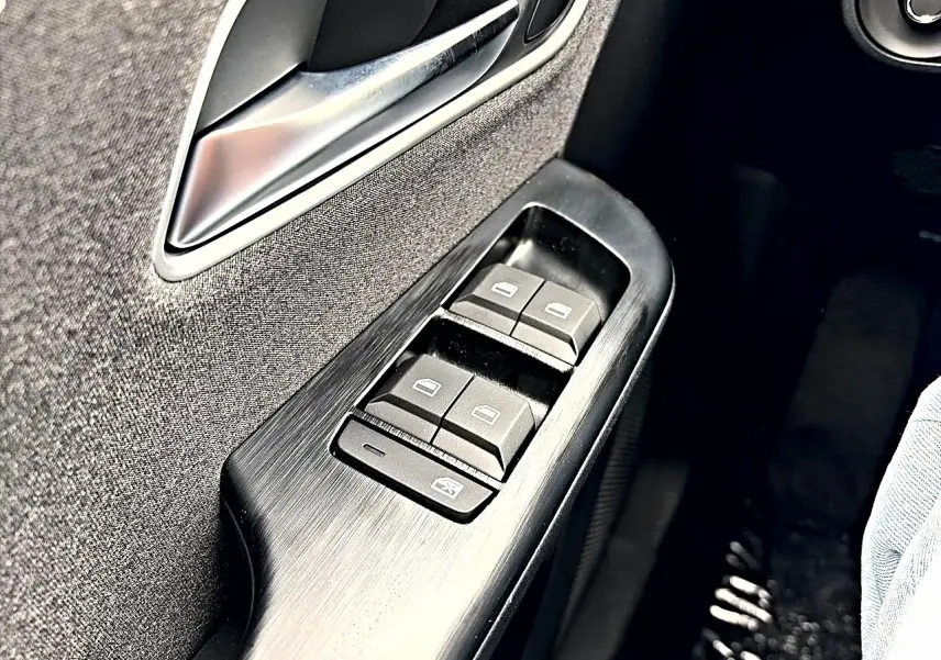 Détail des commandes des vitres électriques côté conducteur dans l’habitacle du MG Motor ZS hybride Camden grey.