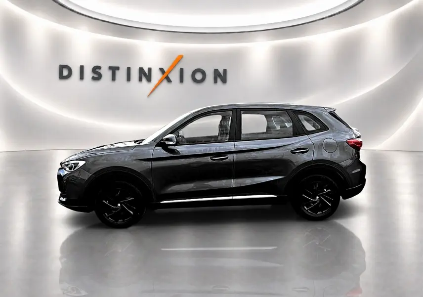 Vue de profil côté gauche du MG ZS Camden grey 1.5 hybrid 197 dans un showroom lumineux avec logo Distinxion en arrière-plan.