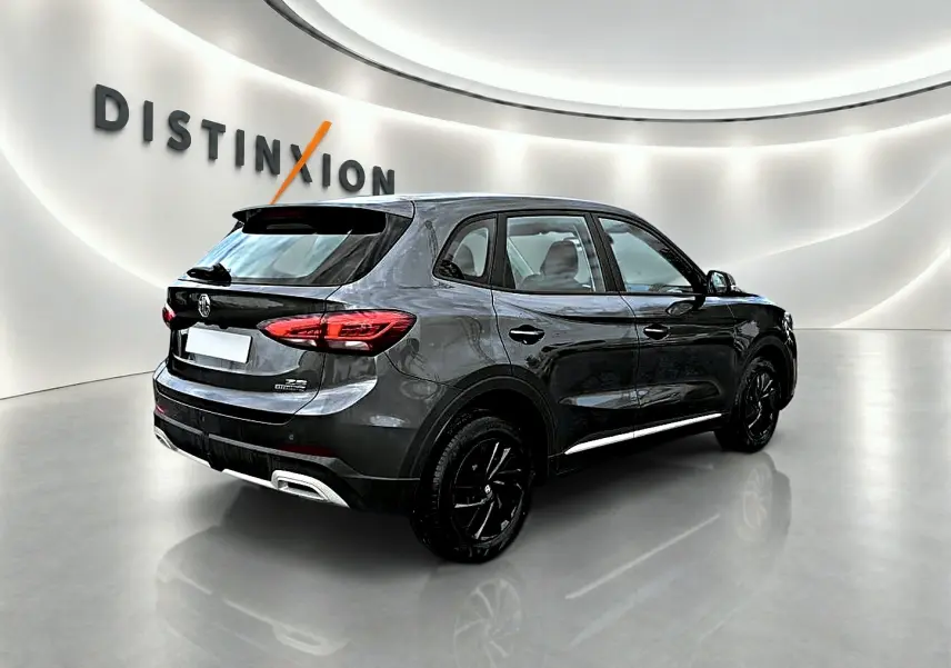 Vue 3/4 arrière droite du MG ZS Camden grey 2026 avec jantes noires et becquet arrière en showroom lumineux.