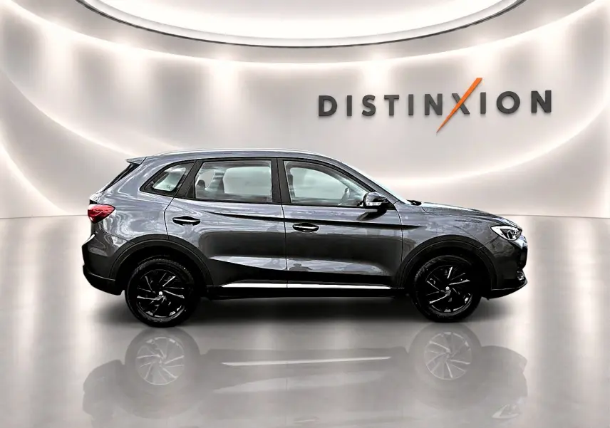 Vue de profil droit du MG ZS 1.5 hybrid 197 Camden grey avec jantes noires dans un showroom lumineux.