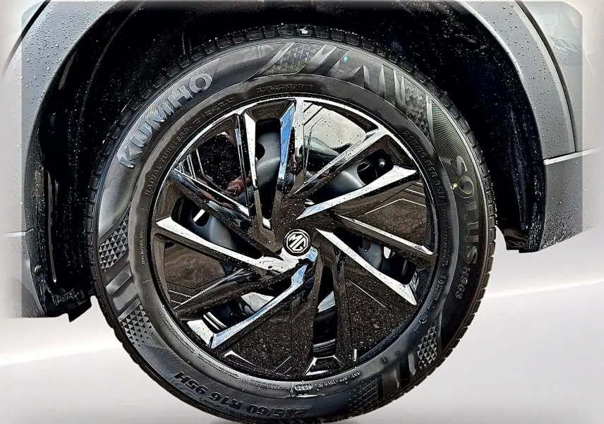 Gros plan sur la roue avant droite du MG ZS Camden grey, mettant en valeur la jante noire brillante au design moderne.