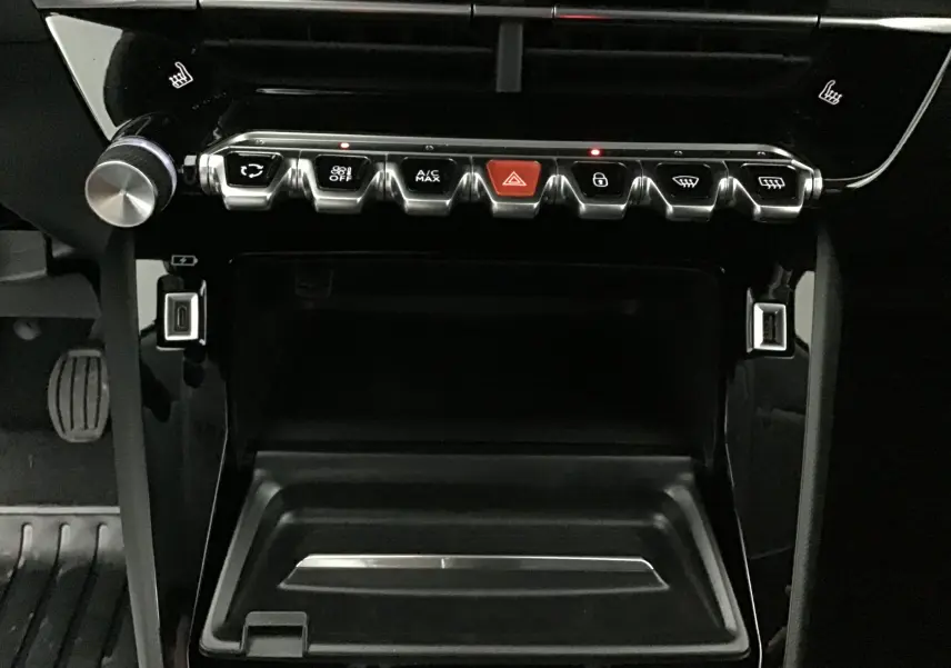 Vue rapprochée de la console centrale noire du Peugeot 208 1.2 PureTech 100 Allure Pack 2024 avec boutons de commande et ports USB.