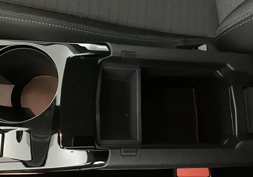 Vue rapprochée de la console centrale noire avec porte-gobelet et rangement du Peugeot 208 blanc 2024.